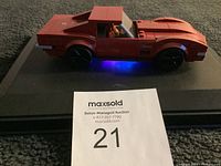 Side view of a red LEGO model of a 1969 Chevrolet Corvette Stingray with a LEGO driver inside and blue light underneath.