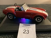 Red Shelby Cobra 427 model car viewed from the side on a display base showing detail and lighting effects.