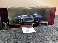 Front view of the blue 1964 Shelby Cobra die cast model inside original packaging showing car details and scale.