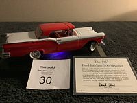 Red and white 1957 Ford Fairlane 500 Skyliner die-cast model on black base with certificate and auction tag.