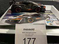 Front and side view of assembled black and orange Lego McLaren Senna GTR model car resting on Lego instruction booklet.