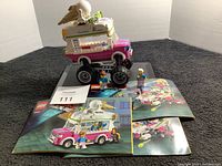 Side view of Lego 70804 Ice Cream Truck with two minifigures and instruction manuals on a black surface.