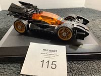 Side view of Lego Batmobile showing orange canopy, golden rims, and bat emblem on front
