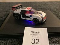 Lego Audi R18 race car model on display stand, showing side and rear details with Audi and RS line logos.