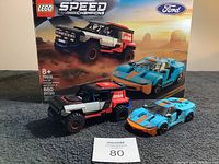 Photo showing both assembled Lego models with box background containing Ford GT Heritage Edition and Bronco R images.