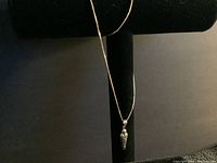 Full view of silver chain necklace hanging on black display with sarcophagus pendant visible.