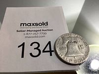 Close-up image of the US Half Dollar coin on auction lot card, showing Liberty Bell and text 'HALF DOLLAR'.