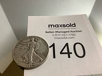 Front angled view of US Walking Liberty half dollar coin showing Lady Liberty, sun, and year 1942 with seller's auction paper behind.