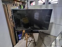 Front view of 50 inch Sceptre TV angled against a wall with power cable visible.