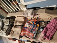 Photo of blanket laid out with folded curtains, bags and scarf.