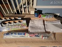 Flag pole with American flag, white folded fabric/netting, small paint can, paintbrush and rollers on display