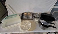 Full view of all items including plastic storage container, metal pans, funnel, divided tray and utensils.