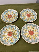 Four yellow and blue flower design plates from Crate & Barrel laid out on green cloth