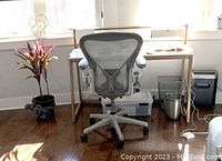 Front view of the grey mesh chair at a desk showing base and casters