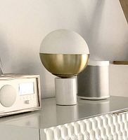 Target round lamp with frosted globe top and marble base shown unlit on a surface alongside speakers and radio.