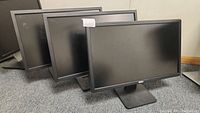 Three Dell monitors arranged next to each other showing front view with screens off.