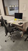 Photo of wheeled office chair positioned at desk with computer and mouse present, showing chair backrest and armrests.