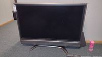 Front view of the Sharp Aquos 45 inch flat screen TV showing the full screen, stand, and the remote on the floor in front.