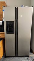 Front view of closed stainless steel side-by-side refrigerator showing dispenser on left door