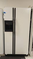 Front view of closed Kenmore side-by-side refrigerator freezer with black handle and ice-water dispenser on left door