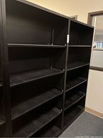 Pair of large black metal adjustable shelving units positioned side by side against a wall.