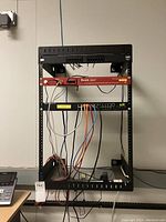 Full front view of metal network rack with connected equipment and Ethernet cables, highlighting the items mounted and wiring.