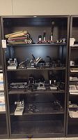 Full metal shelving unit displaying multiple rows of hole punches, staplers, and other office equipment items.