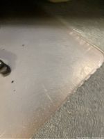View of one transparent office chair mat with rounded corners on carpet, showing some wear and discoloration and chair wheel marks.