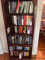 Full bookshelf with books spanning four shelves, visible titles include biographies, political histories, and fiction