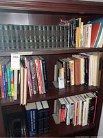 Full shelf with Mark Twain hardcover books and assorted books, two visible metal bookends