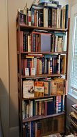 Six shelves filled with hardcover and paperback books, mostly about American Revolution history and George Washington, including books stacked on the floor.