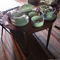 Wooden drop leaf table with various dishes on top, showing table surface and legs.