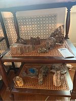 Overview of the fossil rocks and rock figures displayed on a two-tiered wooden shelving unit with cane shelving surfaces.