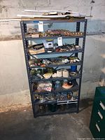 Single metal shelving unit filled with small hardware, tools, cords, and miscellaneous items, showing overall condition and contents.