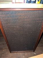 Front view of one large wooden speaker cabinet with woven fabric grill