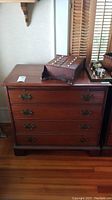 Front view of the wooden dresser showing four drawers and brass handles with a polished finish.