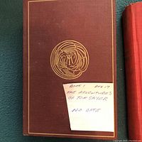 Front cover of The Adventures of Tom Sawyer hardcover book in brown cloth with a circular gold embossed emblem.