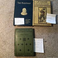 Three vintage hardcover books arranged on carpet: The Habitant and Other French-Canadian Poems (blue cover), Johnnie Courteau (tan cover with illustration), and First Steps in Colloquial French (green cover).