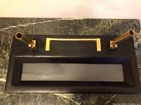 Top view of pen holder showing black textured leather base, brass swivel funnels, and storage cubby.