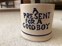 Front of cream-colored small mug with blue spongeware text 'A PRESENT FOR A GOOD BOY' and two blue lines around base.