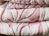 Close-up detail of the pink and white floral jacquard pattern on towel fabric.