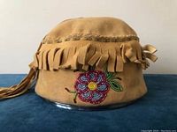 Front view of tan buckskin suede bucket hat showing fringe trim and floral beadwork