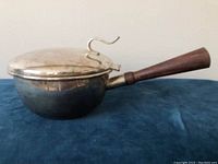 Silver-plated pot with hinged lid closed, showing wood handle and curled decorative lid handle.