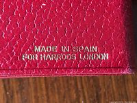 Close-up of stamped 'Made in Spain for Harrods London' on red leather inside wallet.