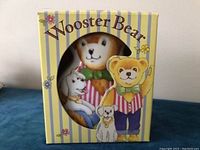 Photo of Wooster Bear piggy bank in its original yellow and white striped box with bear and dog illustrations on front.