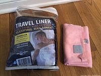 Photo of the packaged Travel Cotton Polyester Sleeping Bag Liner with pillow insert next to the folded pink Lululemon towel.