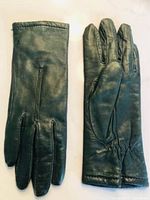 Front and back view of a pair of green genuine leather women's gloves laid flat showing smooth leather surface and detailing.
