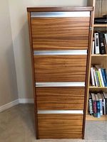Full front view of solid oak filing cabinet with four horizontal drawers featuring wide metal handles.