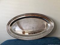 Full front view of large oval silver plated tray on neutral background showing reflective surface and rounded edges.
