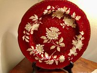 Front view of Wedgwood Ruby Tonquin bone china serving plate with red background and cream floral and gilded design.